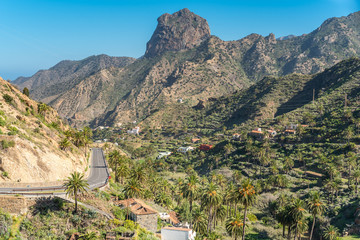 View to the Roque Cano, a famous volcanic neck on the north side of La Gomera. Agriculture in the valley of Vallehermoso, what means the beautiful valley