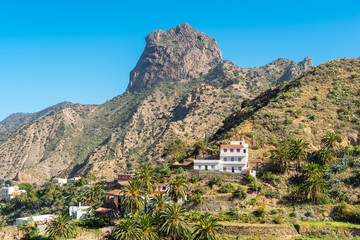 Fototapeta na wymiar View to the Roque Cano, a famous volcanic neck on the north side of La Gomera. Agriculture in the valley of Vallehermoso, what means the beautiful valley