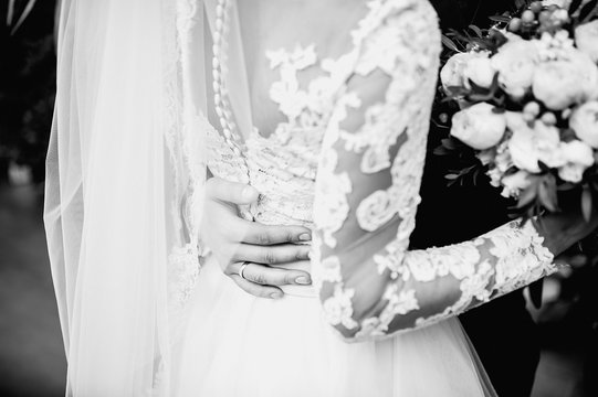 black and white photo of a newlywed couple, groom and bride holding each other's hands with rings