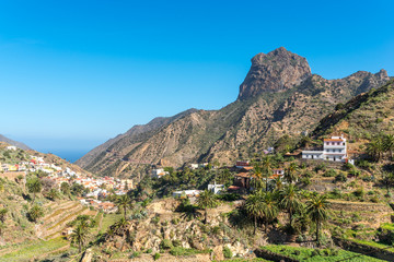 View to the Roque Cano, a famous volcanic neck on the north side of La Gomera. Agriculture in the valley of Vallehermoso, what means the beautiful valley