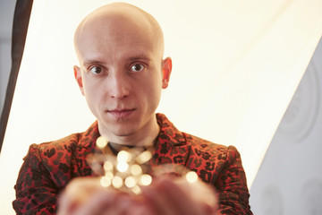 Guy in the classic holiday wear holding New year garlands in front of the camera