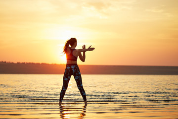 Yoga and fitness. Young woman practicing morning meditation in nature at the beach