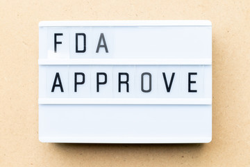 Fototapeta premium White lightbox with word fda approved on wood background