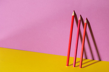A few red pencil with a shadow on a trendy purple and yellow background.space for text