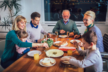 Multi generation family enjoying meal around table at home