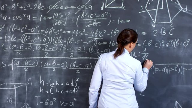 Medium shot of female university professor solving complex calculus problem on blackboard