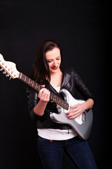 Obraz premium Beautiful dark girl playing guitar in rock style on a black background.