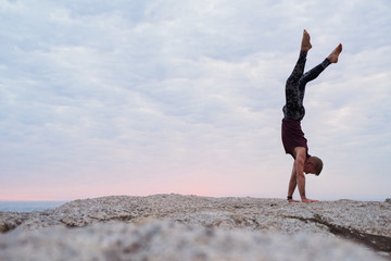 Man doing a hand stand while practicing yoga at dusk