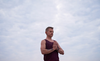 Man meditating during yoga practice against a sky at dusk