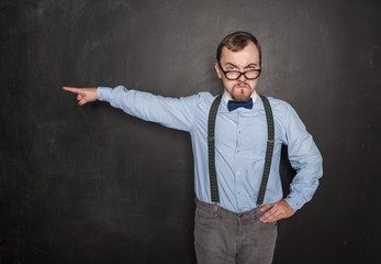 Strict teacher man in eyeglasses pointing out on blackboard