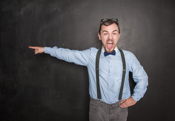 Angry screaming teacher man in eyeglasses pointing out on blackboard