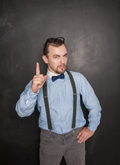 Serious teacher man threaten by finger on blackboard