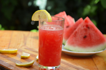 Colorful tropical fresh watermelon smoothie summer drinks in the glasses on wood table background. Refreshing watermelon coсtail with slimon of green foliage. The concept of leisure, travel