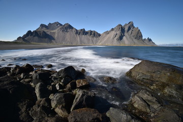 Beautiful view of the Vestrahorn Mountains with black sand and the ocean in front near Höfn in Iceland