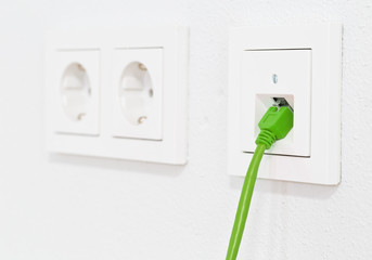 Green network cable in wall outlet for office or private home lan ethernet connection with power...