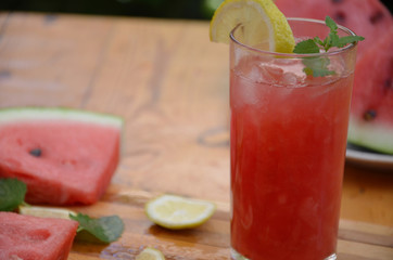 Colorful tropical fresh watermelon smoothie summer drinks in the glasses on wood table background. Refreshing watermelon coсtail with slimon of green foliage. The concept of leisure, travel