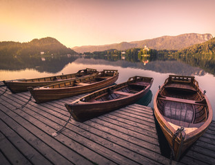 wooden boats at lake bled on a pier in summer during sunrise sunset