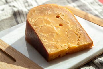 Three years old dark yellow hard Dutch cheese in sun lights