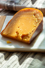 Three years old dark yellow hard Dutch cheese in sun lights