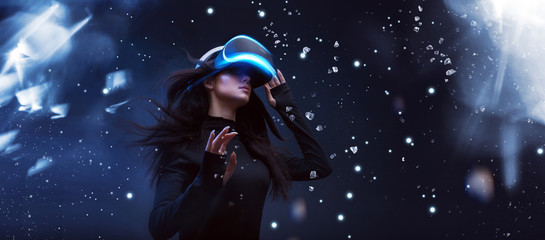 Beautiful woman with flowing hair in futuristic dress over dark background. Girl in glasses of virtual reality. Augmented reality, game, future technology concept. VR.