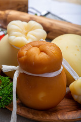 Italian provolone or provola caciocavallo hard and smoked cheeses in teardrop form served on olive tree board close up