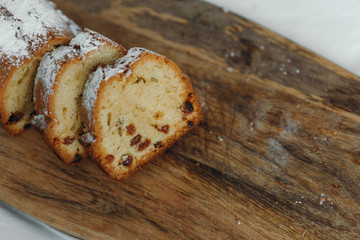 Raisin cake, dusted with icing sugar. Cupcake with raisins on a wooden board.