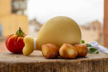 Italian provolone caciocavallo aged and smoked cheeses in teardrop form with yellow houises of old Italian town on background