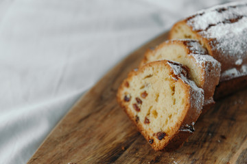 Raisin cake, dusted with icing sugar. Cupcake with raisins on a wooden board.
