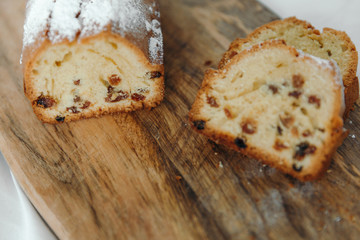 Raisin cake, dusted with icing sugar. Cupcake with raisins on a wooden board.