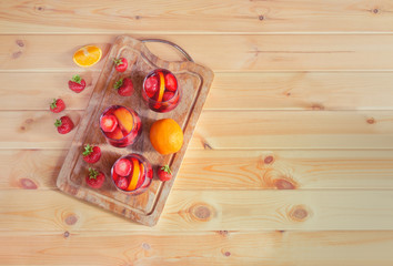 Red wine sangria with fruits in glasses on cutting board. Homemade refreshing fruit sangria over rustic wooden table.
