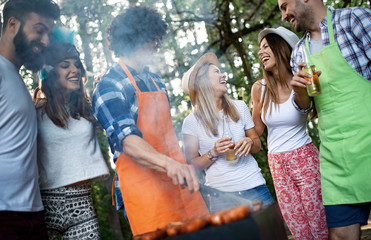 Happy friends camping and having a barbecue in nature
