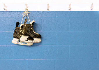 Hockey skates hanging over blue pastel wall in locker room with copy space 