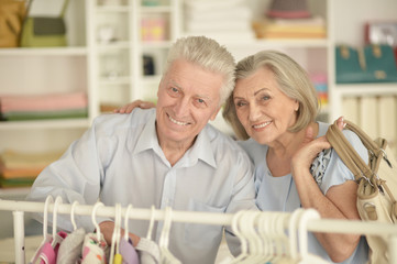 Portrait of happy senior couple near rack with shirts