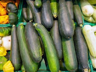 Fresh green zucchini of different varieties are sold on the market.