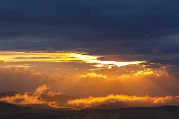Low clouds in backlight over a landscape at sunset