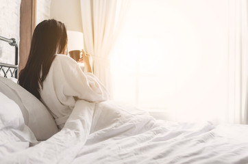 asian woman relaxing in the hotel room, drinking morning coffee, copy space