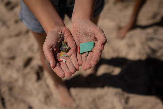 Volunteer holding waste in hand at beach on a sunny day