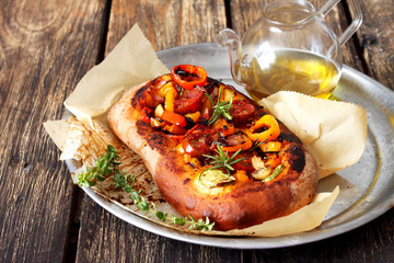 Focaccia with cherry tomatoes , zucchini , onion and peppers