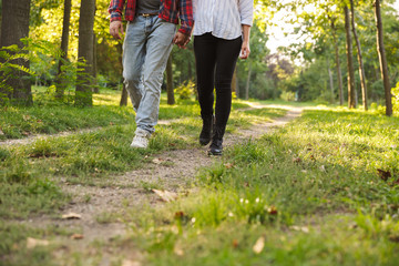 Cropped picture of a young loving couple walking outdoors in a green nature park forest.