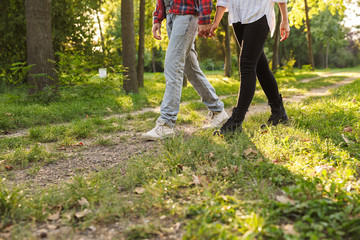 Cropped picture of a young loving couple walking outdoors in a green nature park forest.
