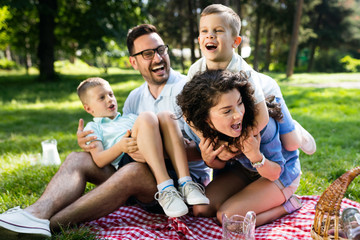Fototapeta premium Happy young family playing on the grass in the park and enjoying picnic