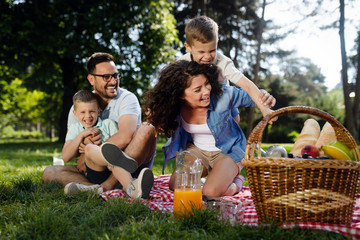 Fototapeta premium Happy male and female playing and enjoying picnic with children outside