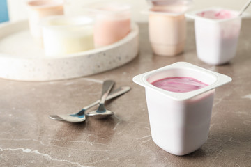 Composition with plastic cups with yogurt on grey table, space for text