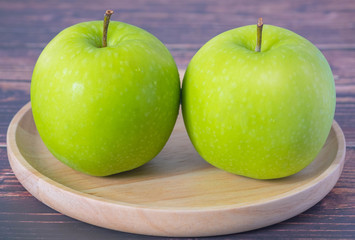 Fresh green apples in dish wooden, on wood table in kitchen.
