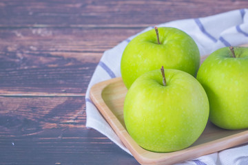 Fresh green apples in dish wooden, with Hand towel on wood table, kitchen in home.
