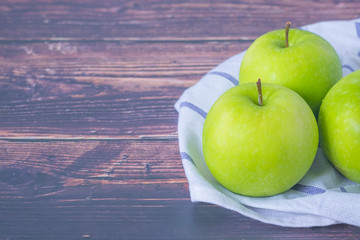 Fresh, Tree green apples with Hand towel on wooden table, in kitchen.
