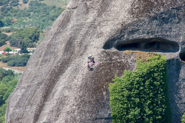 Athletic people are climbing on sharp cliff in Rocks of Meteora, Kalambaka, Greece