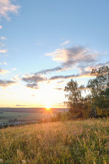 Naklejka premium Beautiful sunset on a hill among the trees overlooking the village