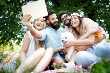 Happy friends in the park having picnic on a sunny day.