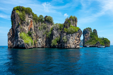 A seascape of a small limestone Thai island in the Andaman Sea, with the flag of Thailand in thA seascape of a beautiful small limestone Thai island in the sparkling Andaman Sea, small boats around